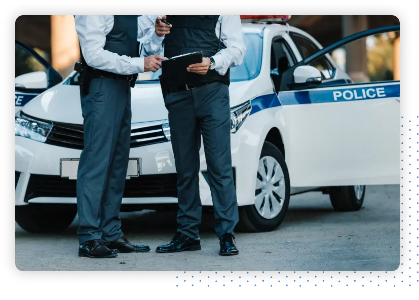 Police officers standing next to a police car